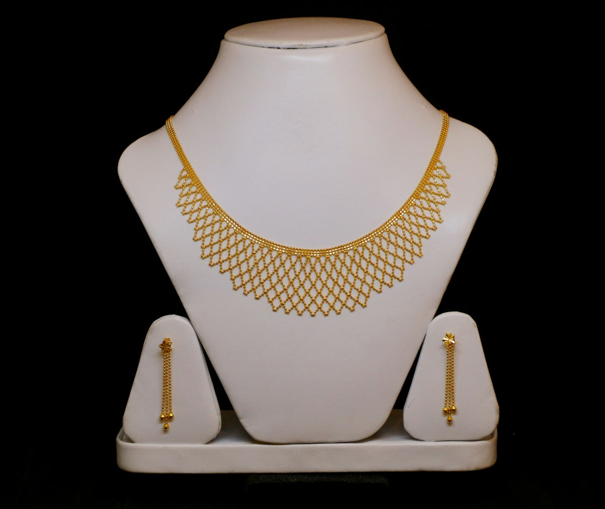 Gold necklace and matching earrings on display.