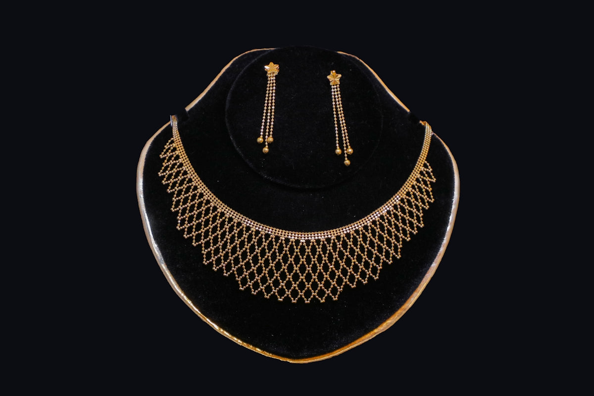 Gold necklace and earrings displayed on black velvet.