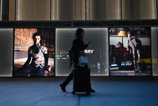 Person walks past illuminated fashion displays at night.