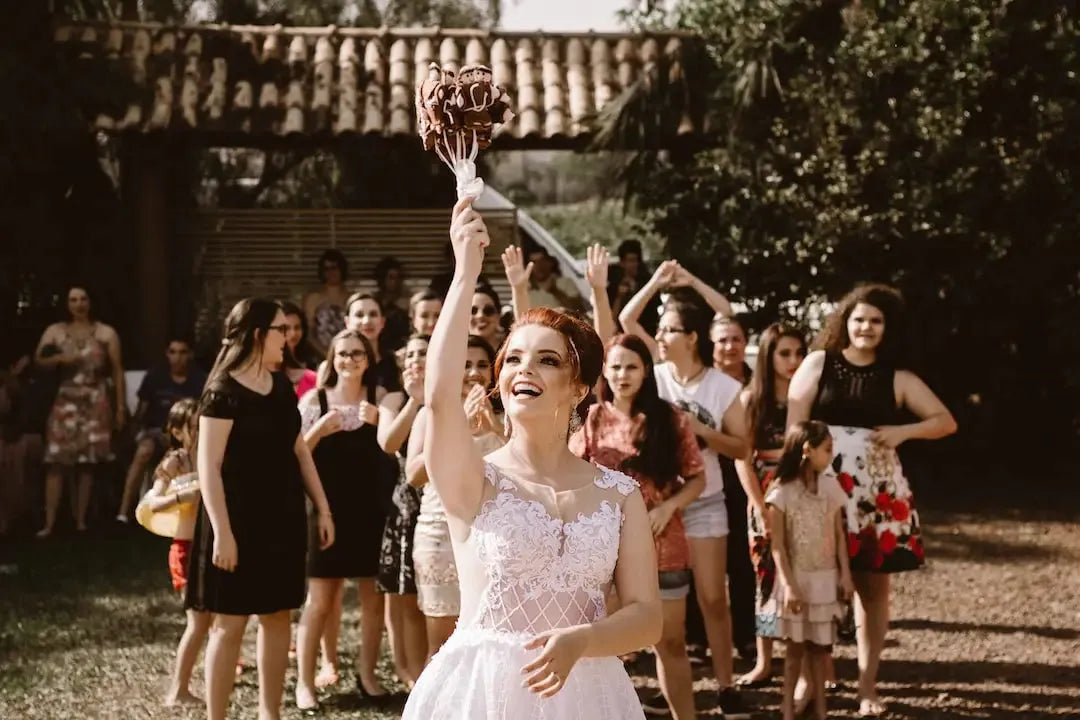 Bride celebrating with friends while holding a bouquet at a wedding surrounded by wedding guest dresses