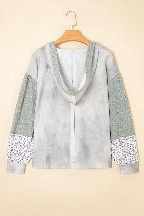 Light gray hoodie with floral cuffs and hem on a beige background