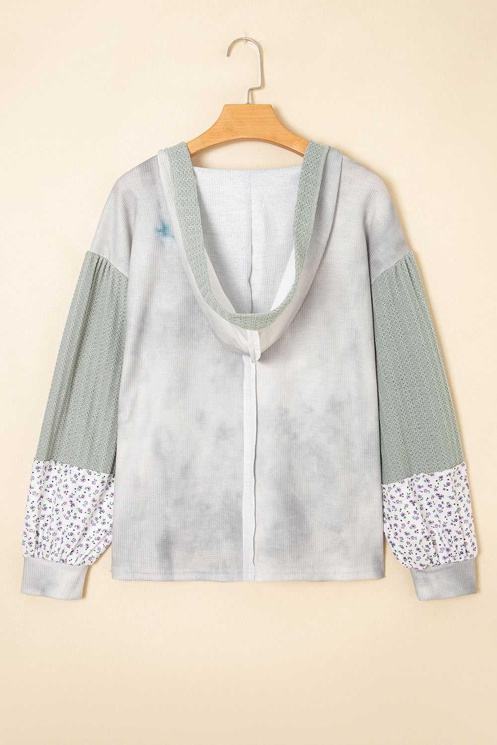 Light gray hoodie with floral cuffs and hem on a beige background