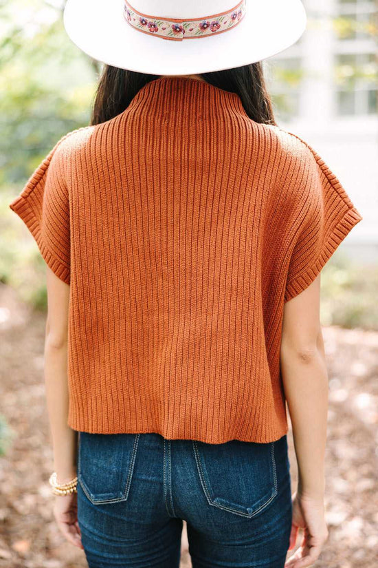 Back view of rust ribbed knit sweater dress with short sleeves, styled with jeans and hat for a cozy outdoor outfit.