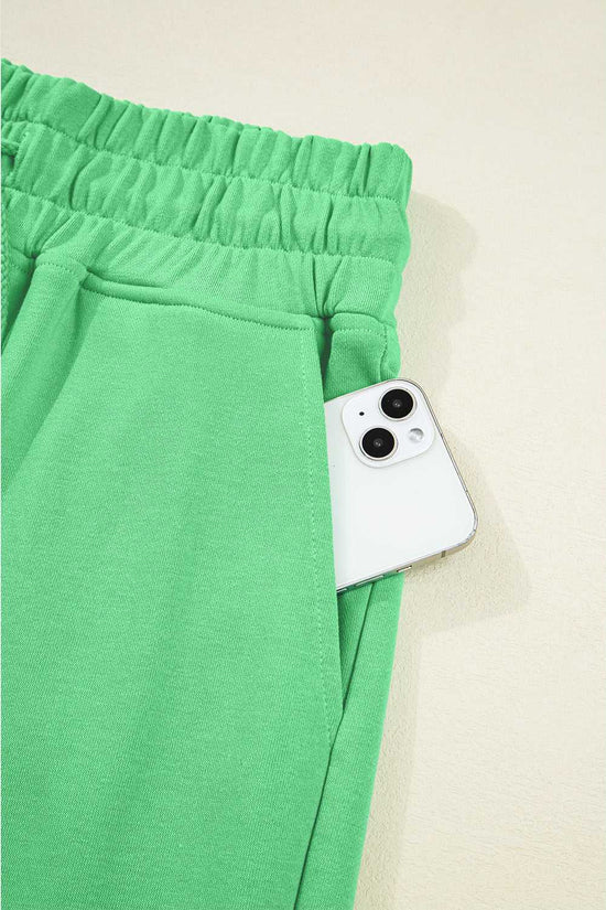 Pocket detail of green Drop Crop Pants with smartphone, emphasizing functionality in stylish loungewear.