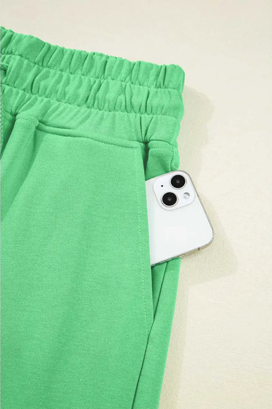 Pocket detail of green Drop Crop Pants with smartphone, emphasizing functionality in stylish loungewear.
