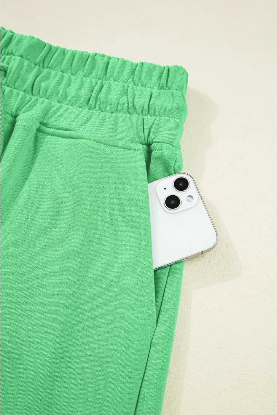 Pocket detail of green Drop Crop Pants with smartphone, emphasizing functionality in stylish loungewear.