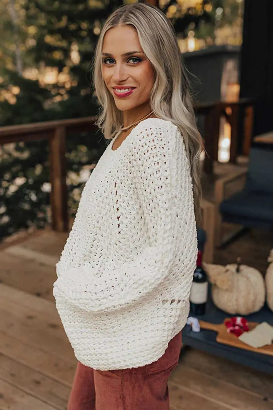 Side view of white wide sleeve hollow knit jumper styled for casual wear, highlighting its lightweight and airy knit design.