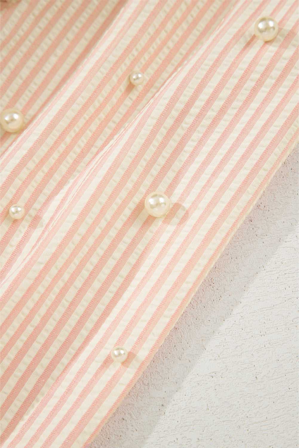 Close-up of pearl embellishments on the striped sleeve of the Bow Cuff Blouse, adding a delicate, whimsical touch.