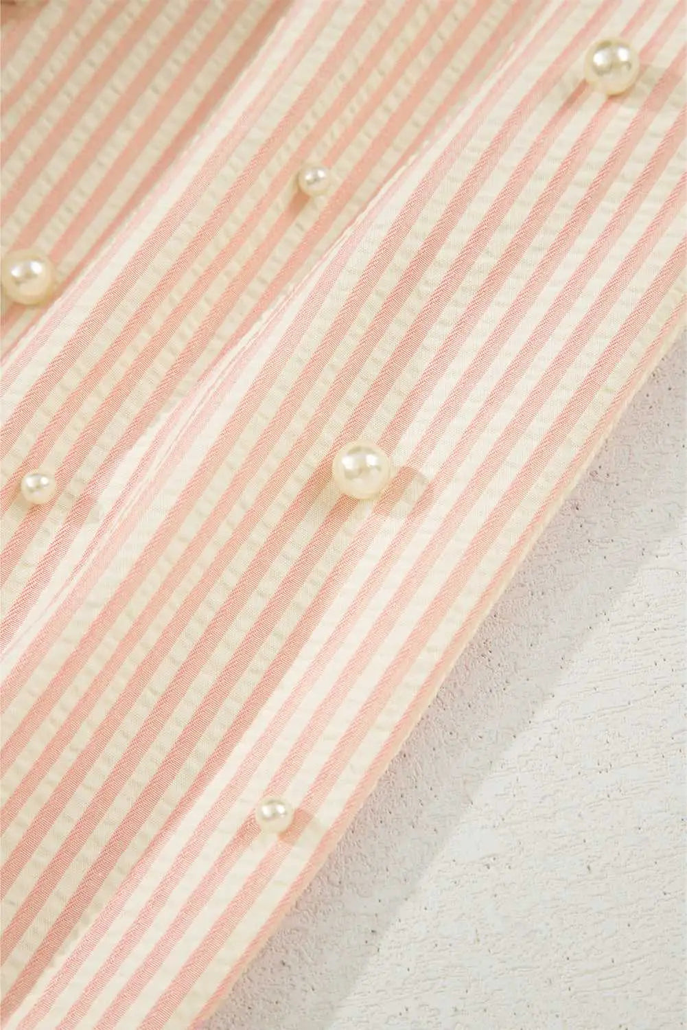 Close-up of pearl embellishments on the striped sleeve of the Bow Cuff Blouse, adding a delicate, whimsical touch.