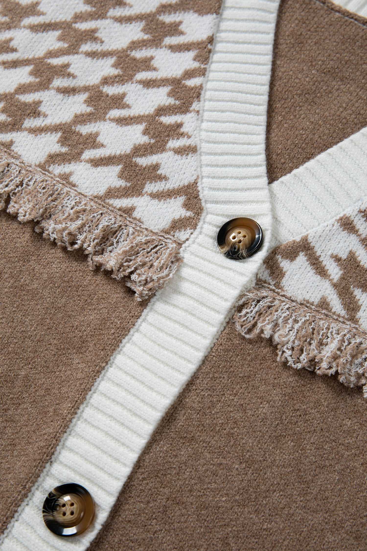 Detail of button placket and fringe trim on khaki houndstooth knit cardigan. Features white ribbed edges for a cozy, casual look.