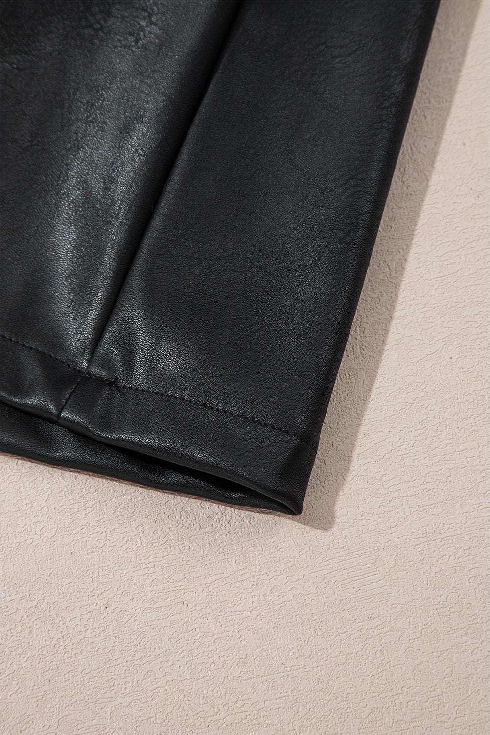 Hem detail of Black Vegan Leather Sleeveless Mini Dress, featuring clean stitching and soft PU leather for a polished look.