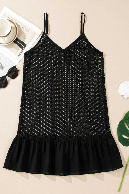 Flat lay of black crochet beach cover-up on beige surface