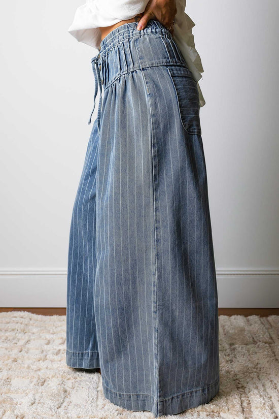 Side profile of women's baggy pinstripe jeans with wide leg silhouette and drawstring waist, offering a trendy and comfortable fit.