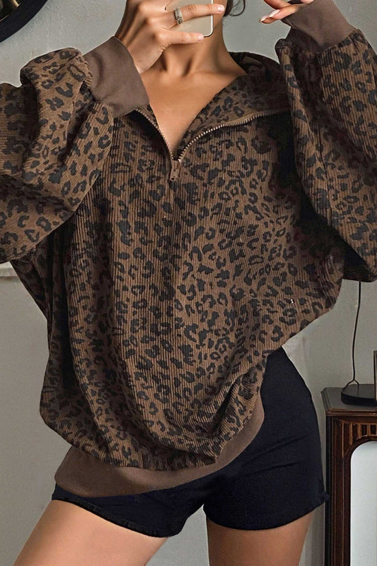 Women's brown leopard print corduroy half-zip jumper styled with black shorts. Cozy fall sweatshirt with ribbed cuffs and relaxed fit.