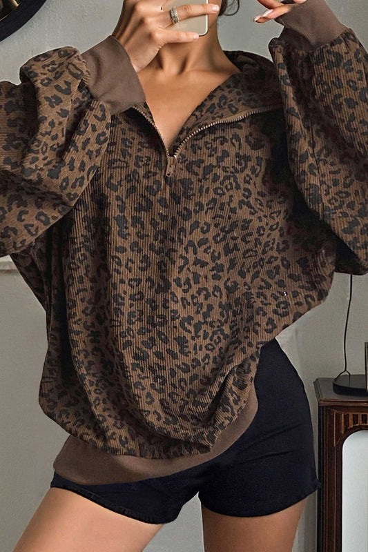 Women's brown leopard print corduroy half-zip jumper styled with black shorts. Cozy fall sweatshirt with ribbed cuffs and relaxed fit.