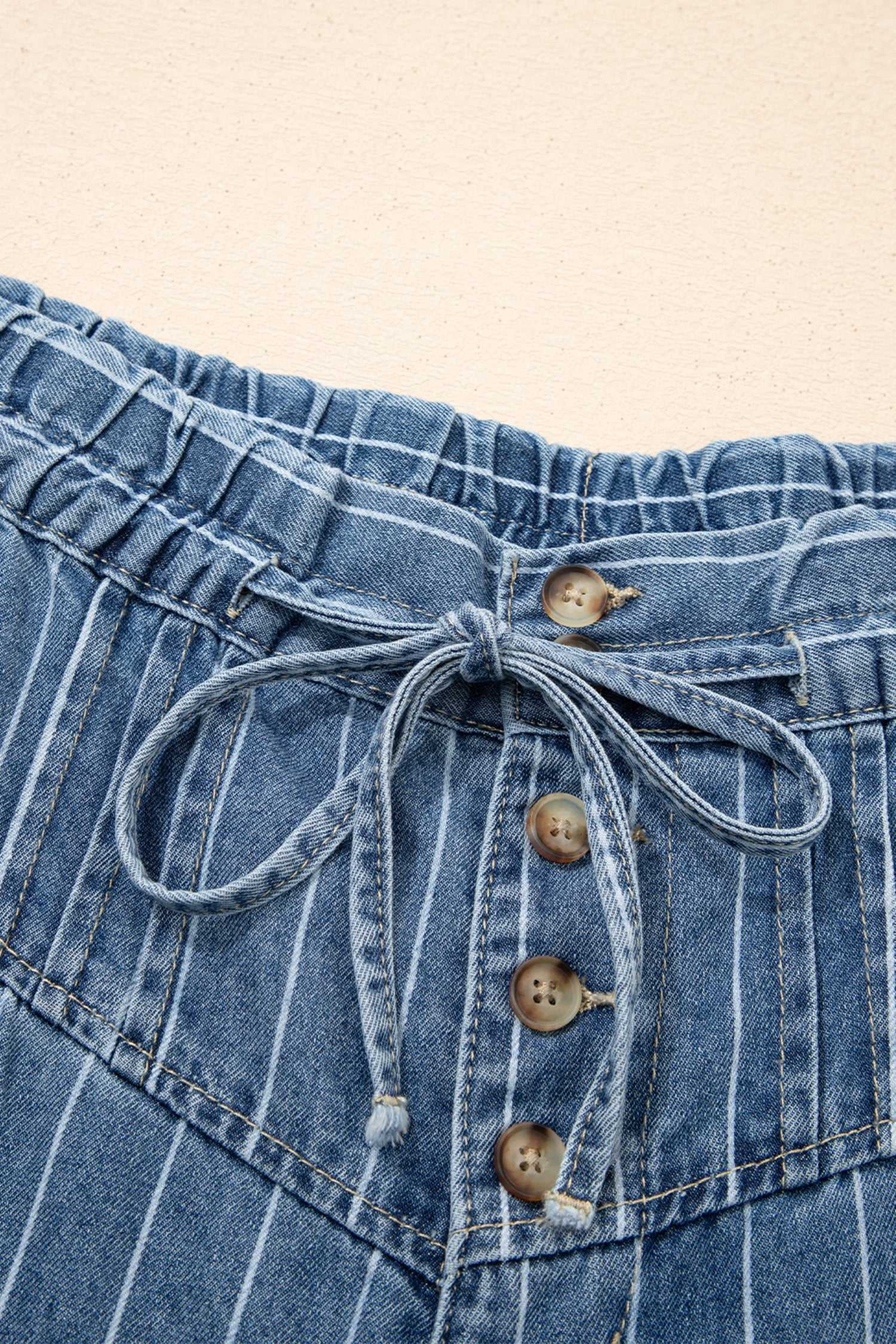 Close-up of drawstring waistband and button fly on women's pinstripe wide leg jeans, showcasing soft cotton denim texture.
