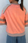 Back view of autumn plaid floral long sleeve top in orange, featuring contrast waffle knit shoulders and plaid sleeve accents.