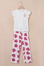 White top with a pink heart design and heart-patterned pants on a beige background
