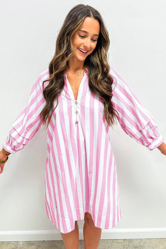 Woman wearing a pink and white striped dress against a plain background
