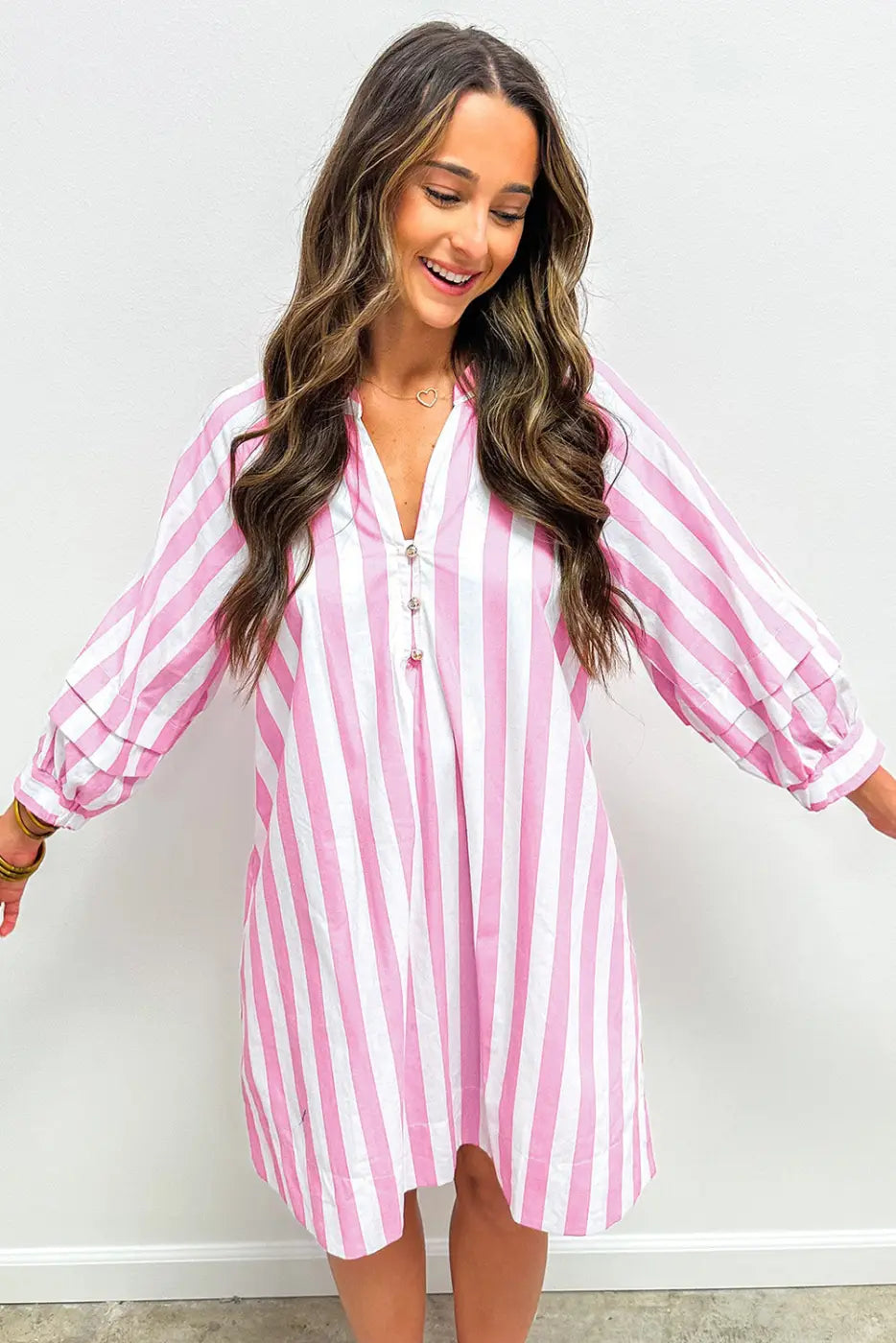 Woman wearing a pink and white striped dress against a plain background