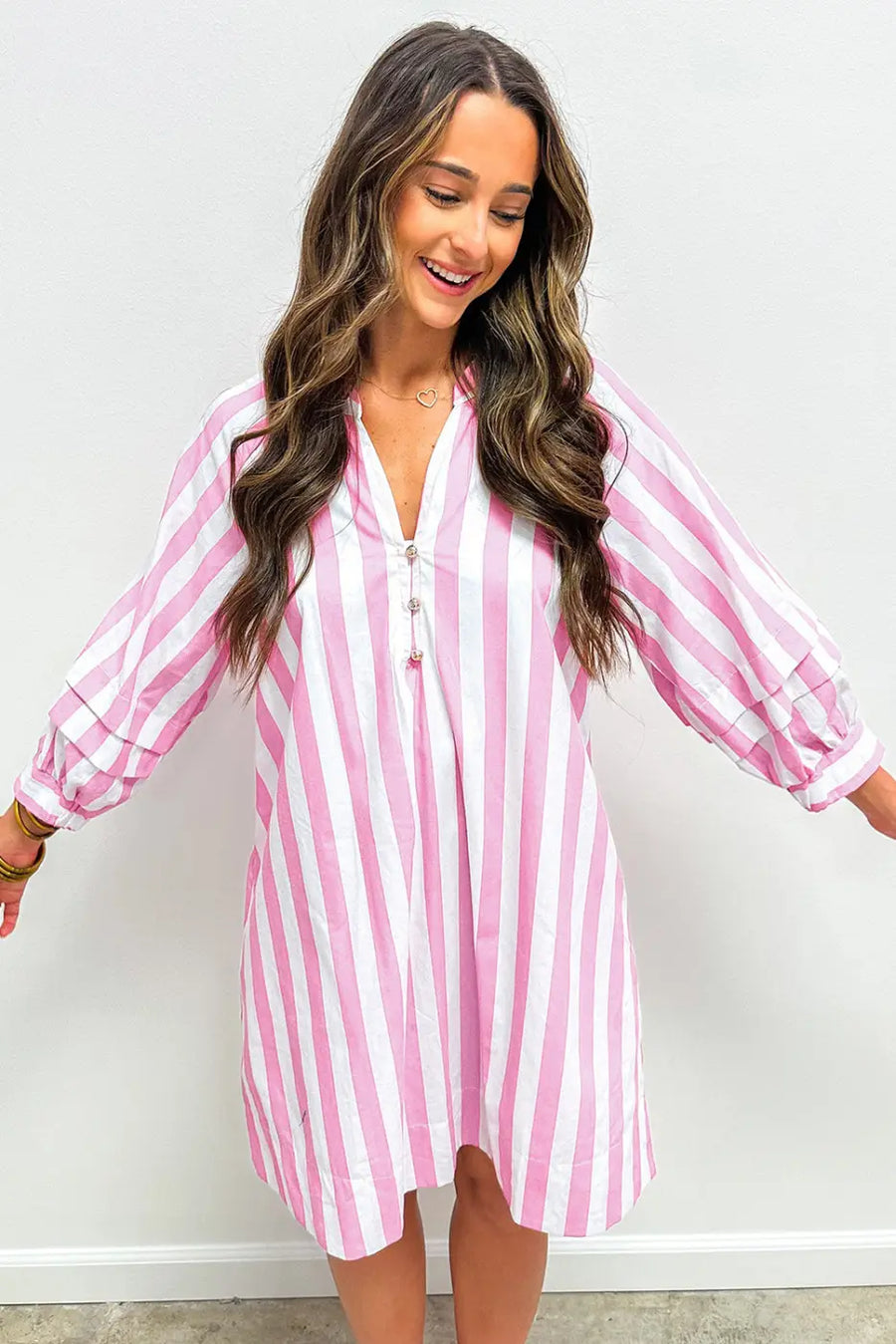 Woman wearing a pink and white striped dress against a plain background