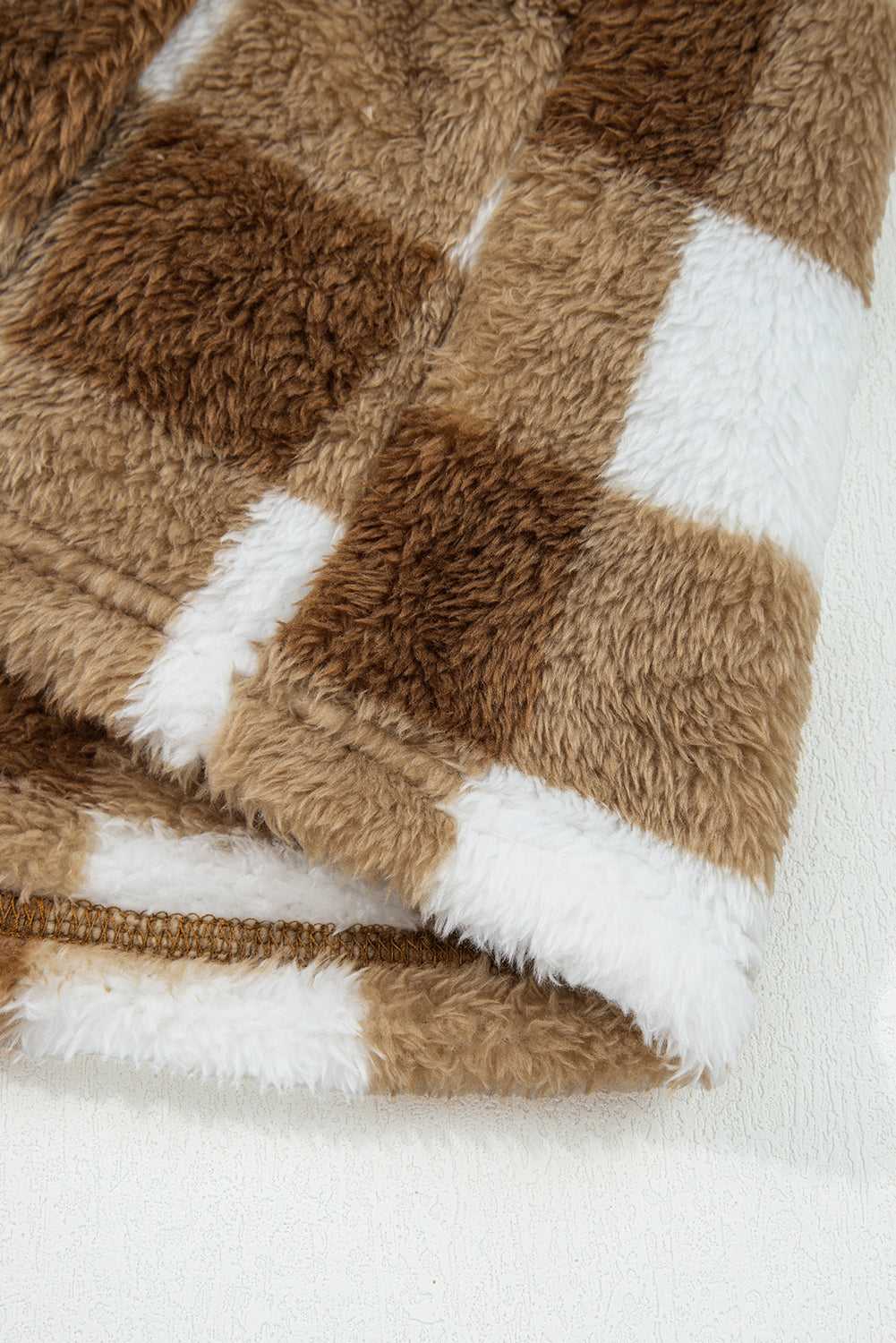 Close-up of soft sherpa fleece fabric on Brown Checkered Cardigan, highlighting plush texture and checkered pattern in brown and white.