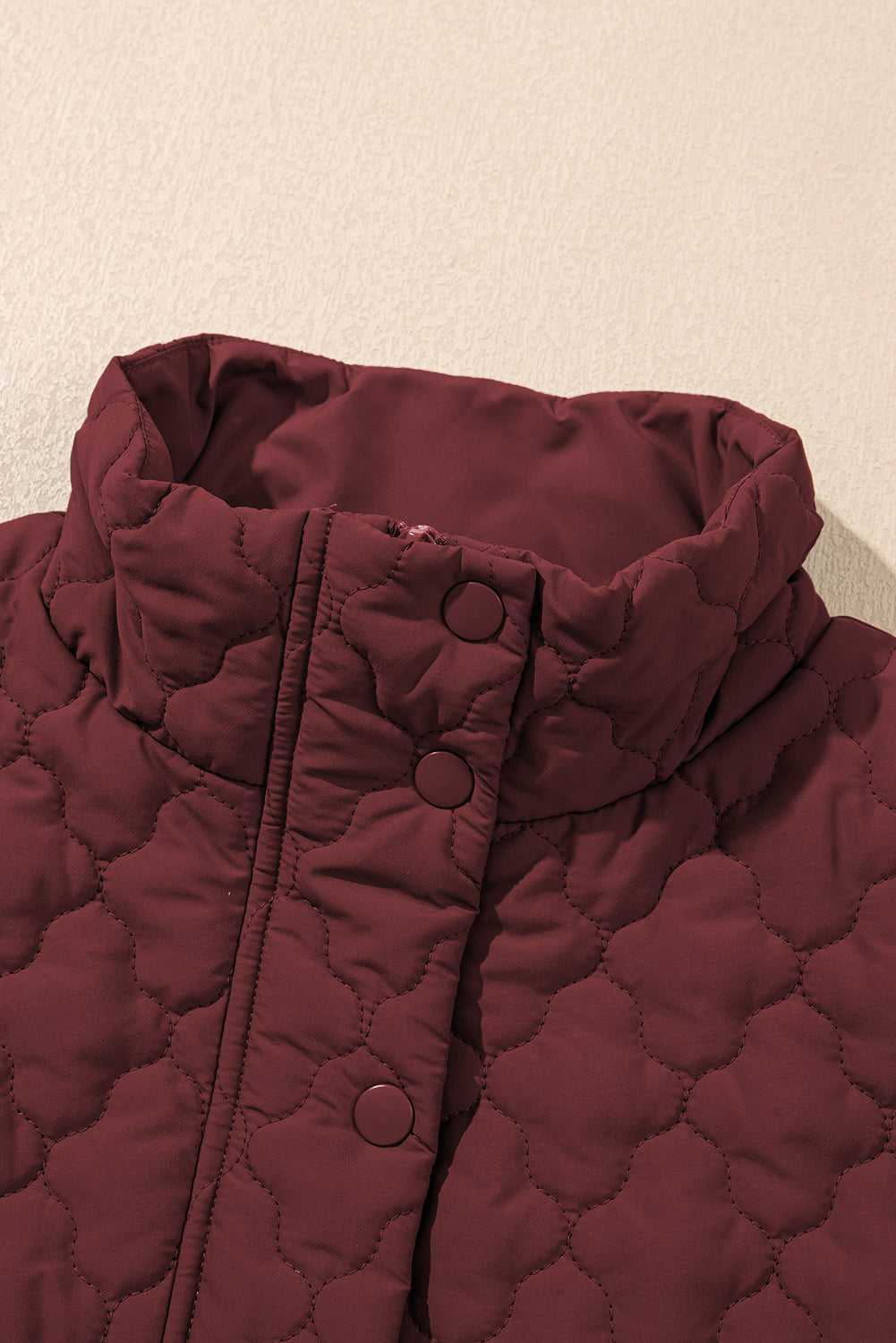 High collar detail of burgundy Flower‑Quilted Winter Gilet with snap buttons, showcasing padded warmth and stylish neckline for winter fashion.