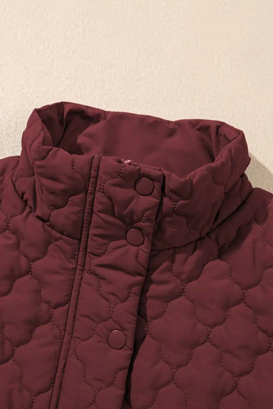 High collar detail of burgundy Flower‑Quilted Winter Gilet with snap buttons, showcasing padded warmth and stylish neckline for winter fashion.