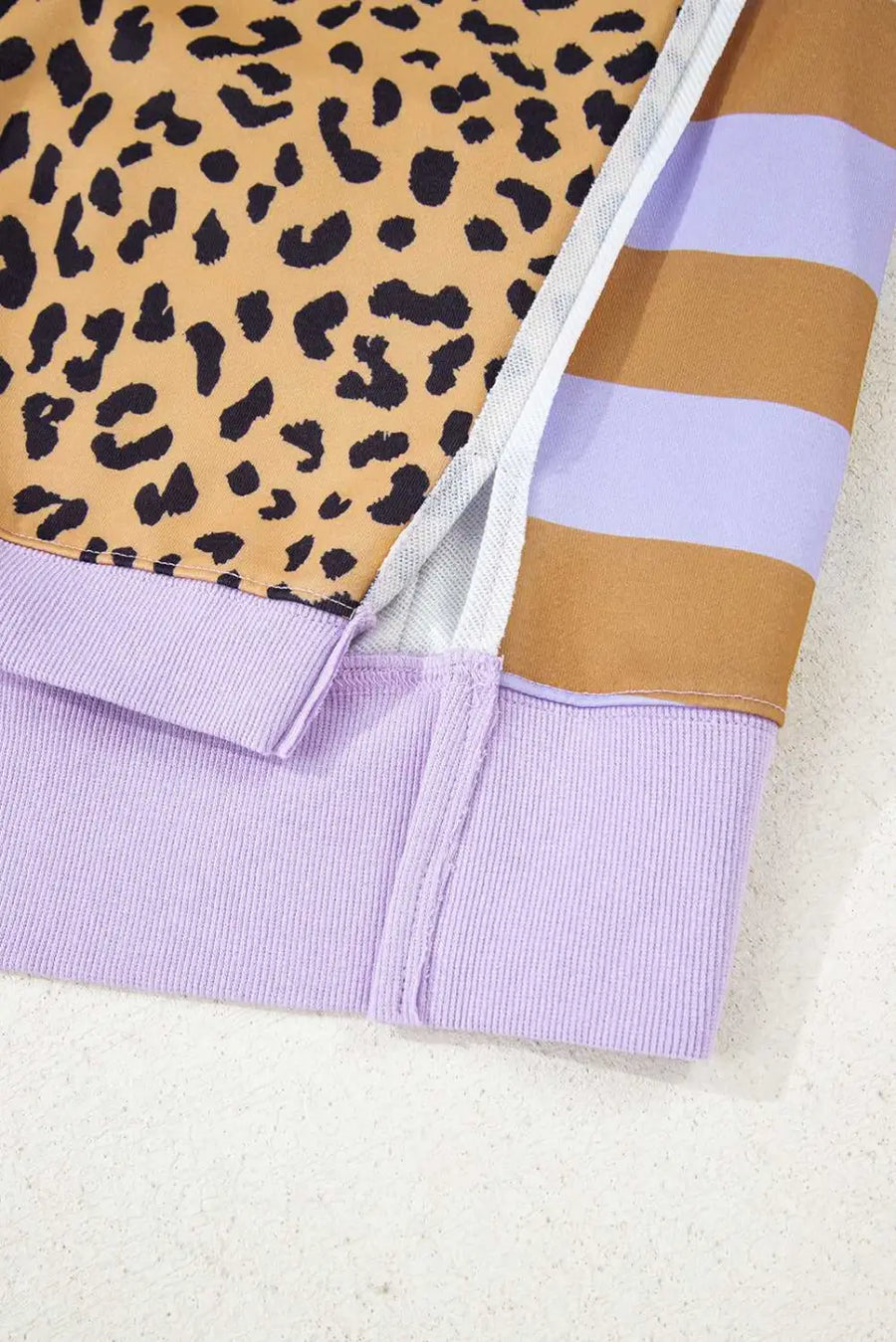 Detail of side slit and stitching on lavender Curve Leopard Stripe Baggy Sweatshirt, emphasizing quality design and comfortable fit.