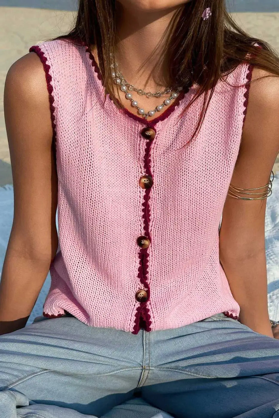 Front view of pink contrast trim knit crop top featuring button-down closure and scalloped edges, perfect for warm-weather outfits.