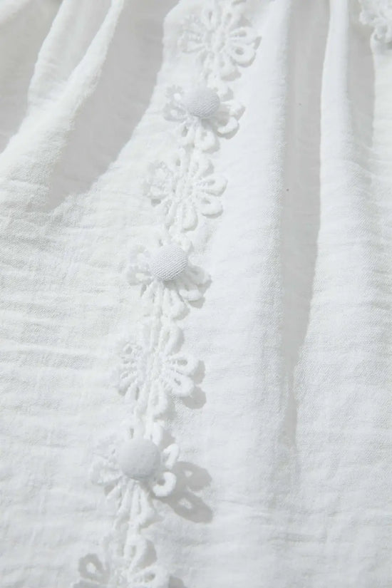 Close-up of the front floral lace trim and fabric buttons on the White Guipure Lace Frill Blouse, emphasizing its elegant patchwork design.