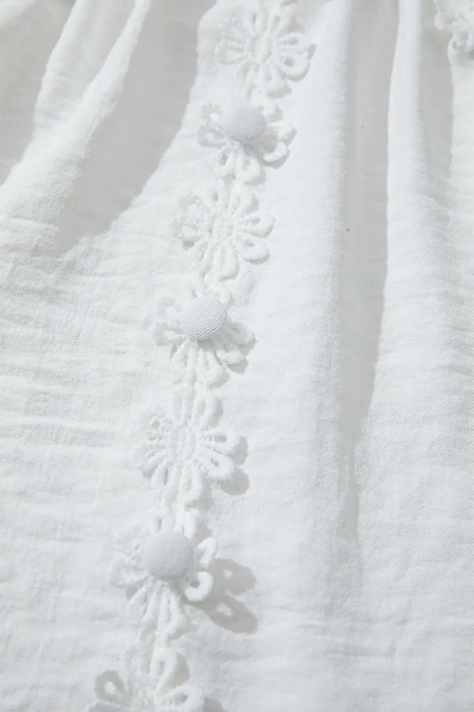 Close-up of the front floral lace trim and fabric buttons on the White Guipure Lace Frill Blouse, emphasizing its elegant patchwork design.