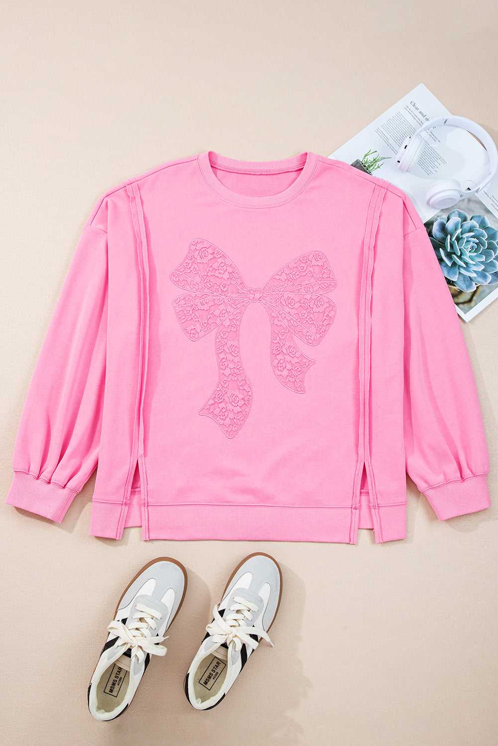 Flat lay of Pink Bow Plus Size Sweatshirt with lace detail, styled with sneakers. A cute and comfy pullover for everyday wear.