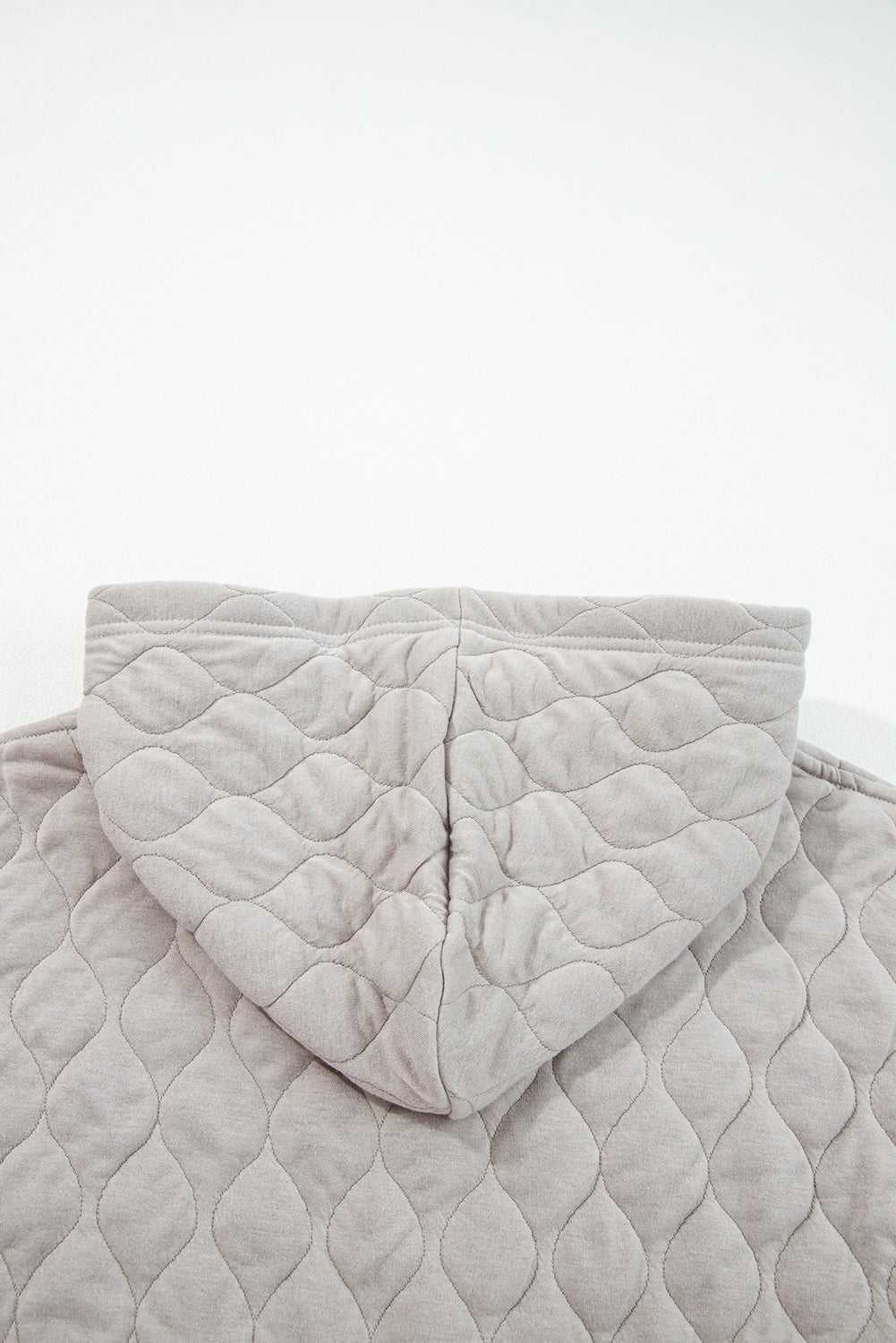 Flat lay of grey quilted hoodie hood detail, showing diamond stitching and soft fabric texture for plus size women's winter apparel.