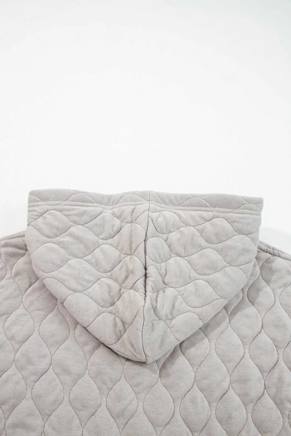 Flat lay of grey quilted hoodie hood detail, showing diamond stitching and soft fabric texture for plus size women's winter apparel.