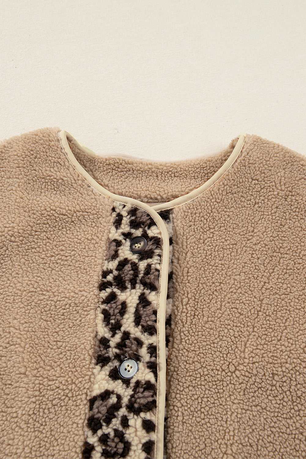 Close-up of neckline and button placket on women’s plush leopard print jacket, featuring sherpa fleece and contrast trim.