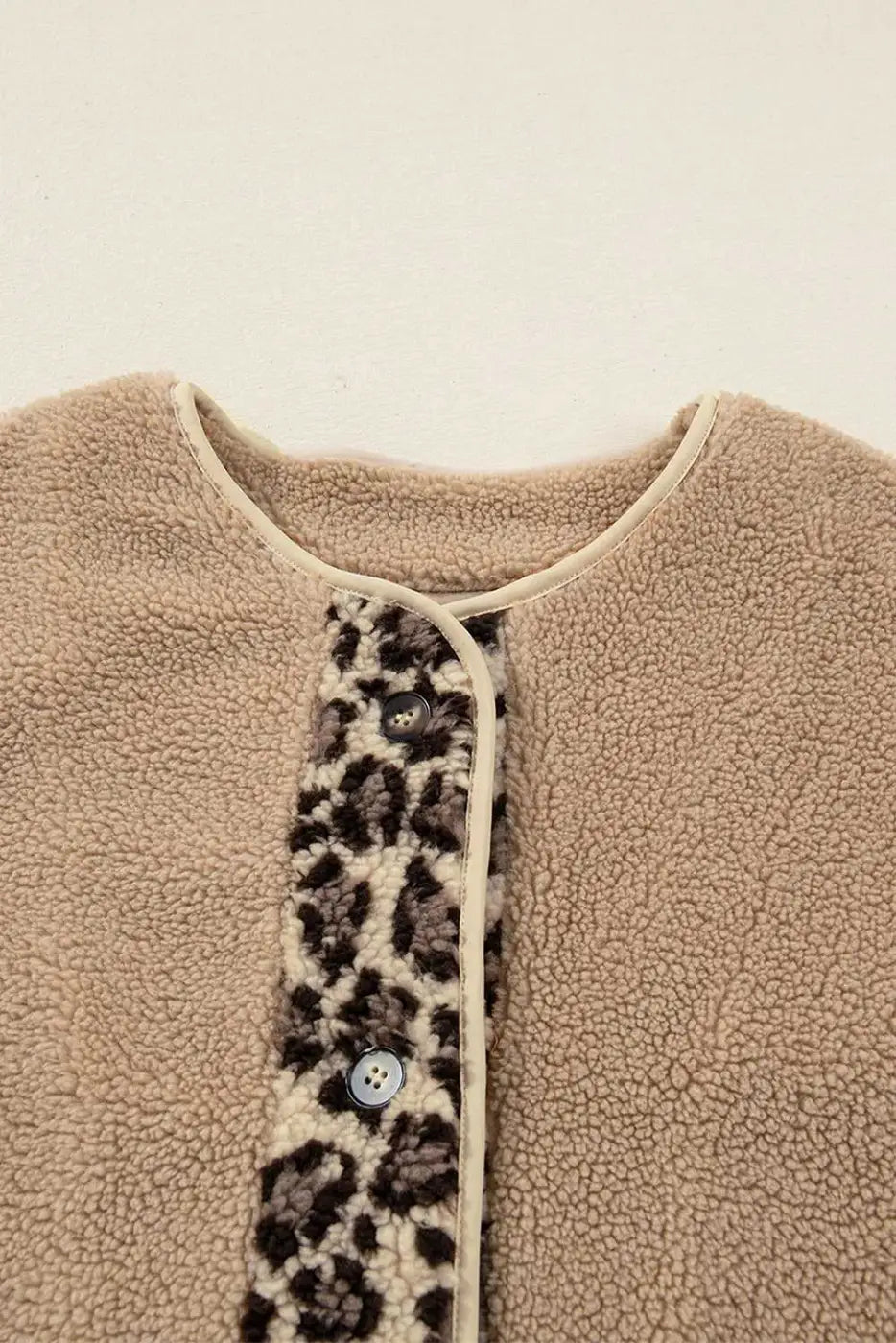 Close-up of neckline and button placket on women’s plush leopard print jacket, featuring sherpa fleece and contrast trim.