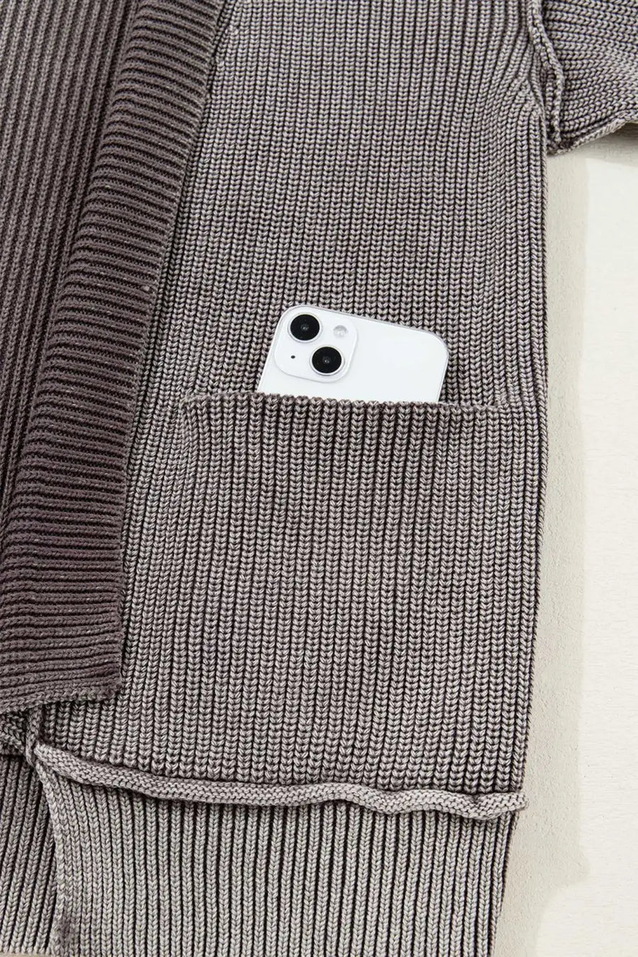 Detail of front pocket on brown stonewash knit cardigan with smartphone inside, emphasizing functionality and casual design.