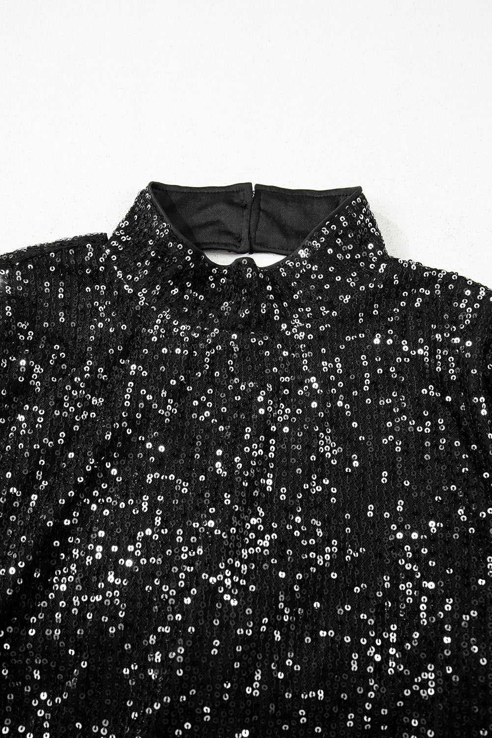 Detail of high neckline and back button closure on black sequin bell sleeve blouse, ideal for festive and elegant styling.