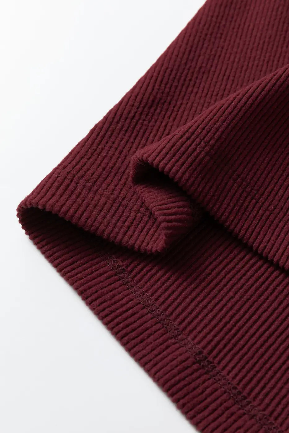 Folded edge of brown ribbed long sleeve crop top emphasizing soft knit and stretch fit. A versatile piece for casual wardrobes.