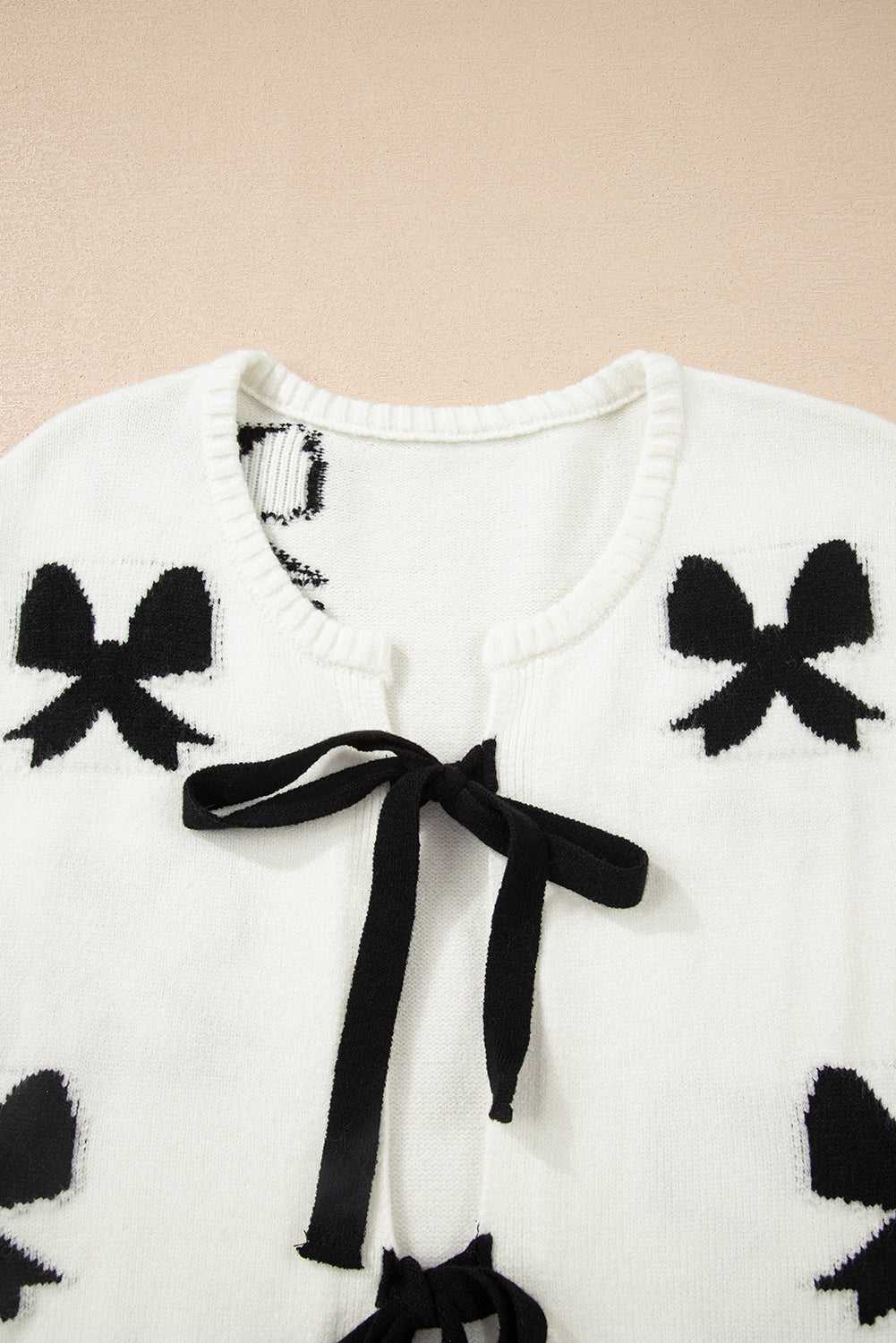 Close-up of neckline and bow details on White Bow‑Lace Knit Cardigan, showing soft knit fabric and delicate black ribbon accents.
