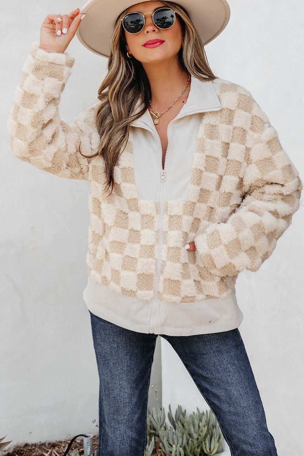 Woman wearing a Corduroy Sherpa Jacket over a white shirt with a beige hat and sunglasses, standing against a white background.