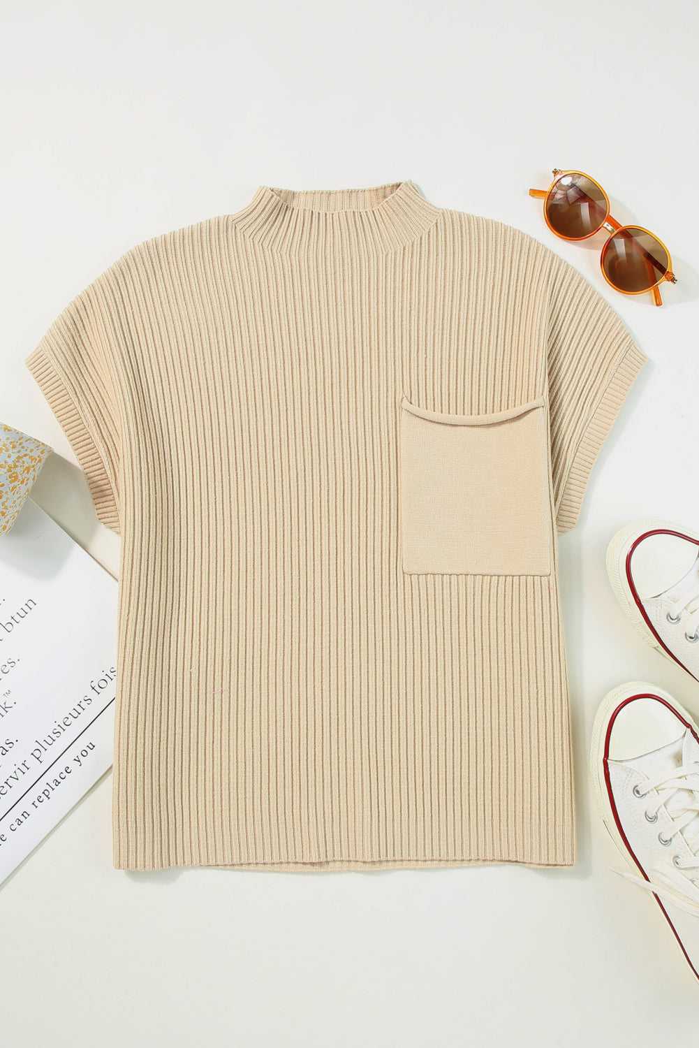 Flat lay of oatmeal ribbed knit sweater dress with short sleeves and chest pocket, styled with sunglasses and sneakers.