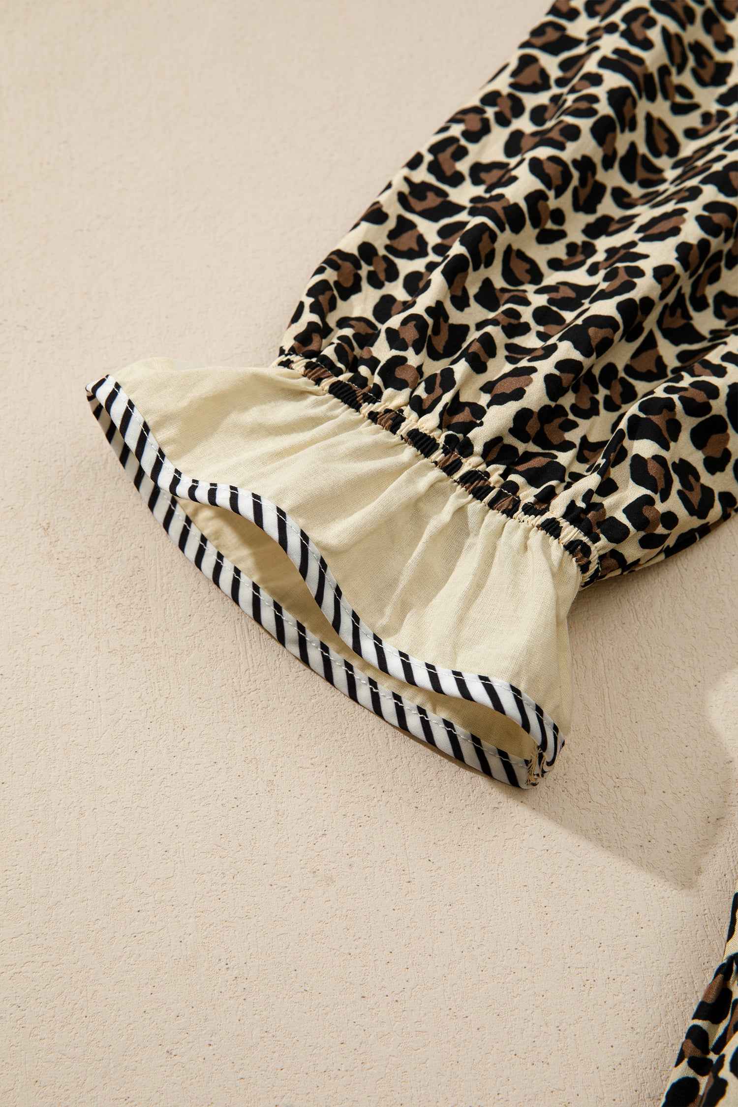 Detailed view of sleeve cuff on Leopard Print Striped Trim Mini Dress with ruffled hem and striped trim for stylish summer fashion.