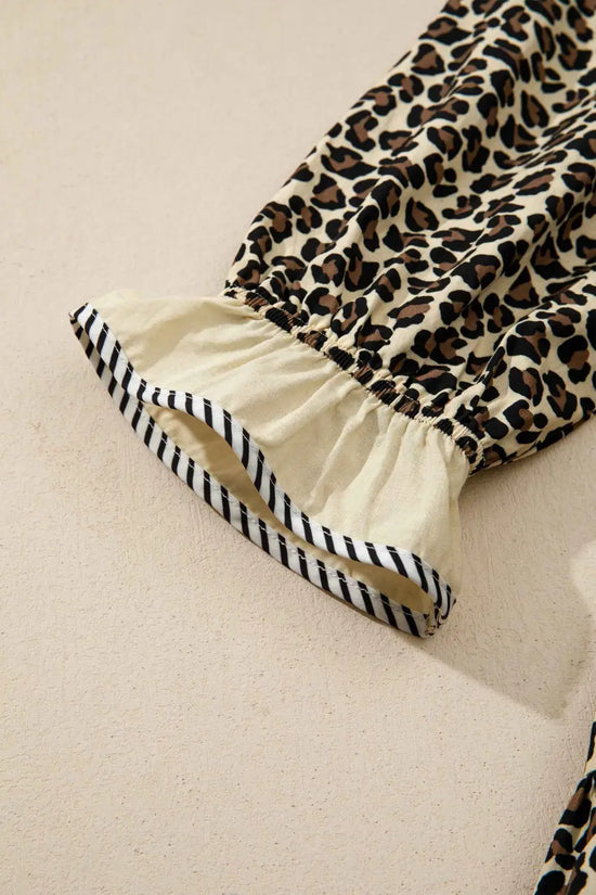 Detailed view of sleeve cuff on Leopard Print Striped Trim Mini Dress with ruffled hem and striped trim for stylish summer fashion.