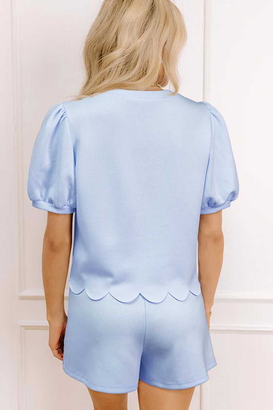 Woman wearing a light blue skort set with scalloped details.