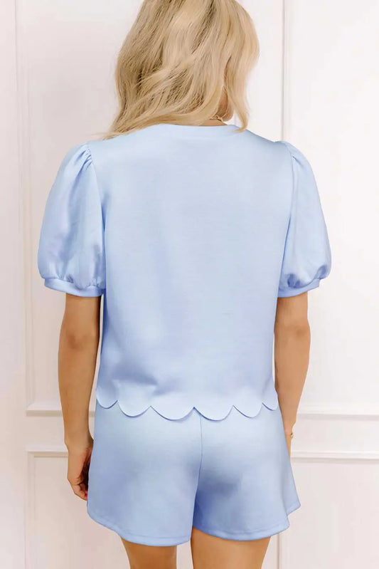 Woman wearing a light blue skort set with scalloped details.