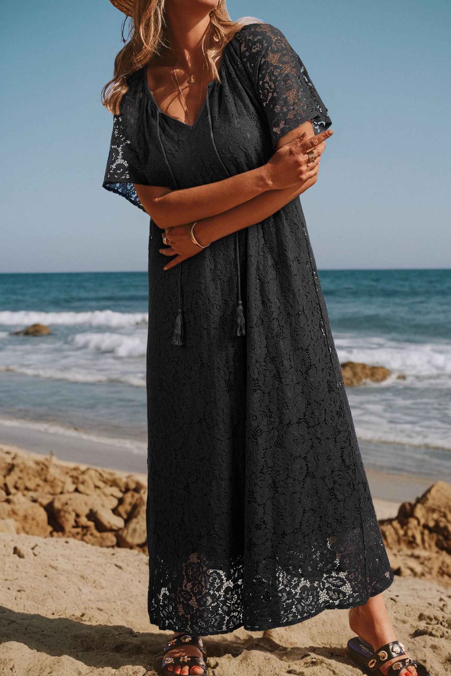 Black Lace Overlay Maxi Sundress with floral lace detail and tassel ties, styled for a beach vacation. Lightweight H-line silhouette for summer comfort.