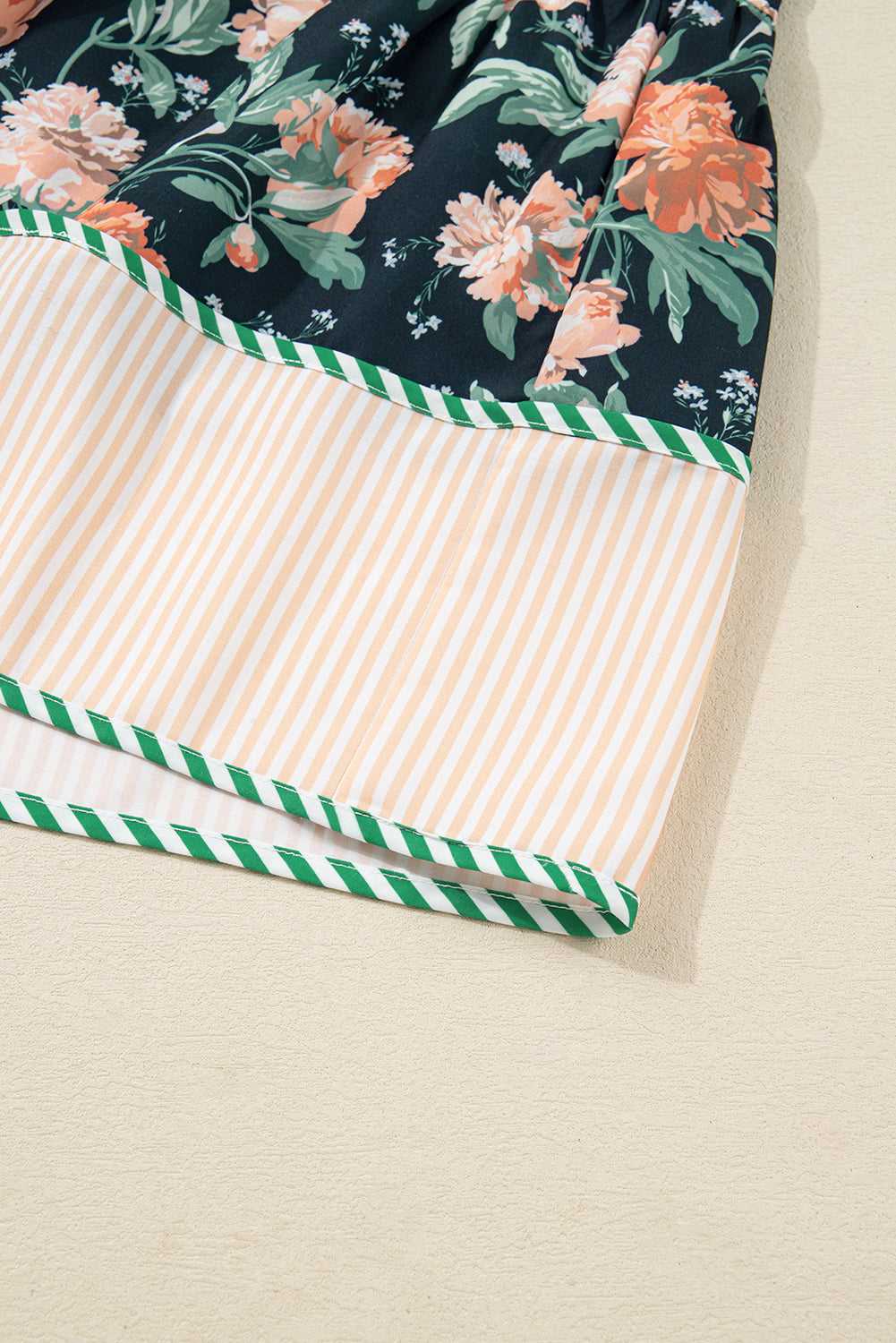 Hem detail of Ladies Blue Floral Shift Mini Dress with peach striped panel and green piping, adding contrast to the floral spring design.