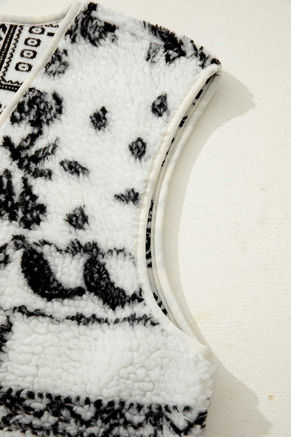 Armhole detail of the beige sherpa vest with black paisley print, emphasizing soft sherpa fabric and clean stitching.